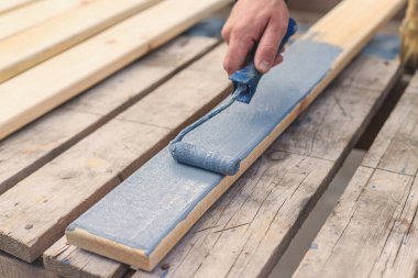 Bir adam bir tahtayı boyayla boyuyor. Seçici odaklanma. İnsanlar.