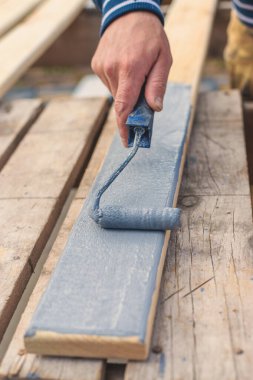 Bir adam bir tahtayı boyayla boyuyor. Seçici odaklanma. İnsanlar.