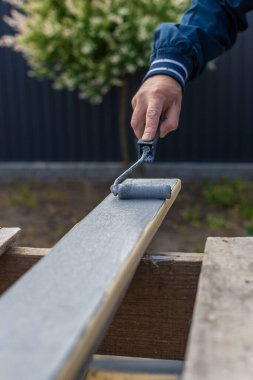 Bir adam bir tahtayı boyayla boyuyor. Seçici odaklanma. İnsanlar.