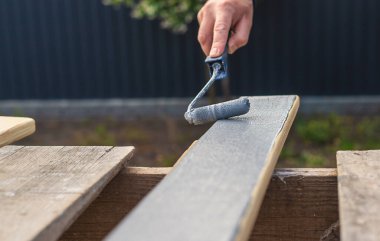 Bir adam bir tahtayı boyayla boyuyor. Seçici odaklanma. İnsanlar.