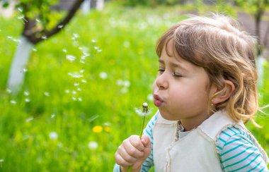 Çocuk parkta karahindiba üflüyor. Seçici odaklanma. Alerji çocuğu..