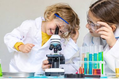 Test tüpleri, reaktörleri ve mikroskobu olan bir çocuğun laboratuvar incelemesi. Seçici odaklanma. çocuk.