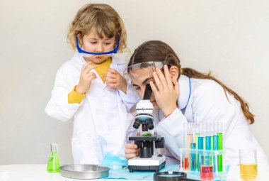 Test tüpleri, reaktörleri ve mikroskobu olan bir çocuğun laboratuvar incelemesi. Seçici odaklanma. çocuk.