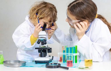 Test tüpleri, reaktörleri ve mikroskobu olan bir çocuğun laboratuvar incelemesi. Seçici odaklanma. çocuk.