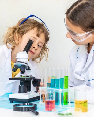 Test tüpleri, reaktörleri ve mikroskobu olan bir çocuğun laboratuvar incelemesi. Seçici odaklanma. çocuk.