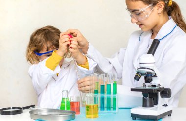 Test tüpleri, reaktörleri ve mikroskobu olan bir çocuğun laboratuvar incelemesi. Seçici odaklanma. çocuk.