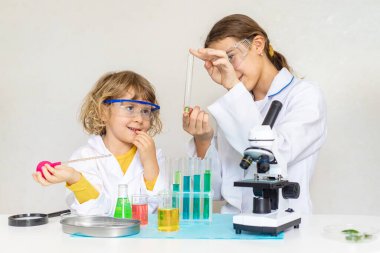 Test tüpleri, reaktörleri ve mikroskobu olan bir çocuğun laboratuvar incelemesi. Seçici odaklanma. çocuk.