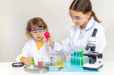 Test tüpleri, reaktörleri ve mikroskobu olan bir çocuğun laboratuvar incelemesi. Seçici odaklanma. çocuk.