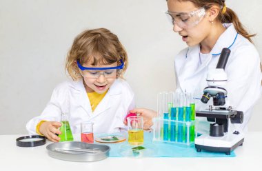 Test tüpleri, reaktörleri ve mikroskobu olan bir çocuğun laboratuvar incelemesi. Seçici odaklanma. çocuk.