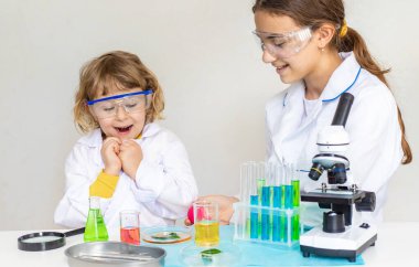 Test tüpleri, reaktörleri ve mikroskobu olan bir çocuğun laboratuvar incelemesi. Seçici odaklanma. çocuk.