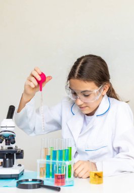 Test tüpleri, reaktörleri ve mikroskobu olan bir çocuğun laboratuvar incelemesi. Seçici odaklanma. çocuk.