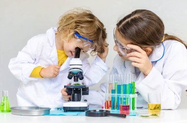 Test tüpleri, reaktörleri ve mikroskobu olan bir çocuğun laboratuvar incelemesi. Seçici odaklanma. çocuk.