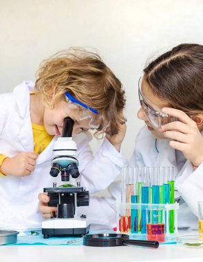 Test tüpleri, reaktörleri ve mikroskobu olan bir çocuğun laboratuvar incelemesi. Seçici odaklanma. çocuk.