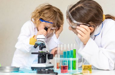 Test tüpleri, reaktörleri ve mikroskobu olan bir çocuğun laboratuvar incelemesi. Seçici odaklanma. çocuk.