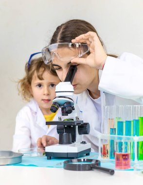 Test tüpleri, reaktörleri ve mikroskobu olan bir çocuğun laboratuvar incelemesi. Seçici odaklanma. çocuk.