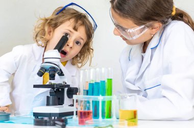 Test tüpleri, reaktörleri ve mikroskobu olan bir çocuğun laboratuvar incelemesi. Seçici odaklanma. çocuk.