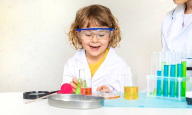 Test tüpleri, reaktörleri ve mikroskobu olan bir çocuğun laboratuvar incelemesi. Seçici odaklanma. çocuk.