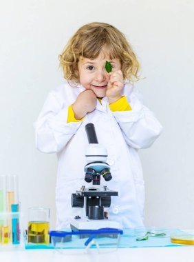 Test tüpleri, reaktörleri ve mikroskobu olan bir çocuğun laboratuvar incelemesi. Seçici odaklanma. çocuk.