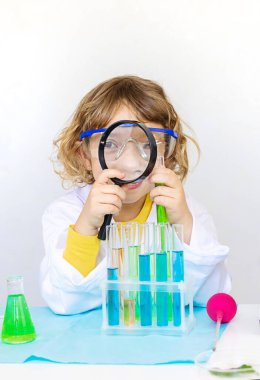 Test tüpleri, reaktörleri ve mikroskobu olan bir çocuğun laboratuvar incelemesi. Seçici odaklanma. çocuk.