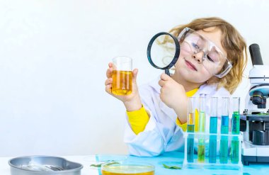 Test tüpleri, reaktörleri ve mikroskobu olan bir çocuğun laboratuvar incelemesi. Seçici odaklanma. çocuk.