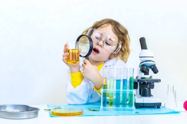 Test tüpleri, reaktörleri ve mikroskobu olan bir çocuğun laboratuvar incelemesi. Seçici odaklanma. çocuk.