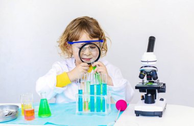 Test tüpleri, reaktörleri ve mikroskobu olan bir çocuğun laboratuvar incelemesi. Seçici odaklanma. çocuk.