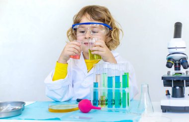 Test tüpleri, reaktörleri ve mikroskobu olan bir çocuğun laboratuvar incelemesi. Seçici odaklanma. çocuk.