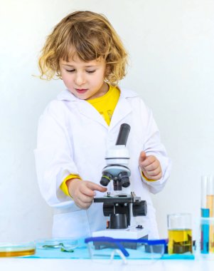 Test tüpleri, reaktörleri ve mikroskobu olan bir çocuğun laboratuvar incelemesi. Seçici odaklanma. çocuk.