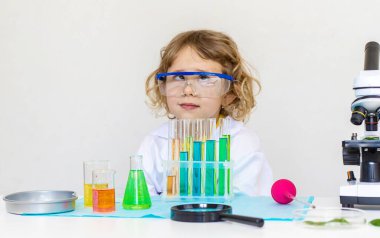 Test tüpleri, reaktörleri ve mikroskobu olan bir çocuğun laboratuvar incelemesi. Seçici odaklanma. çocuk.