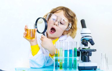 Test tüpleri, reaktörleri ve mikroskobu olan bir çocuğun laboratuvar incelemesi. Seçici odaklanma. çocuk.