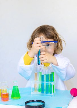 Test tüpleri, reaktörleri ve mikroskobu olan bir çocuğun laboratuvar incelemesi. Seçici odaklanma. çocuk.