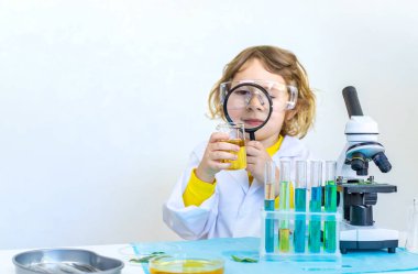 Test tüpleri, reaktörleri ve mikroskobu olan bir çocuğun laboratuvar incelemesi. Seçici odaklanma. çocuk.