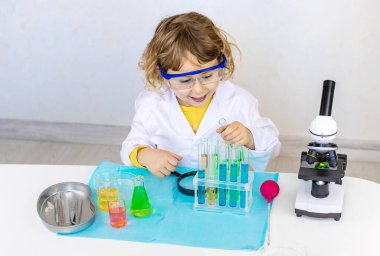 Test tüpleri, reaktörleri ve mikroskobu olan bir çocuğun laboratuvar incelemesi. Seçici odaklanma. çocuk.
