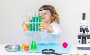 Test tüpleri, reaktörleri ve mikroskobu olan bir çocuğun laboratuvar incelemesi. Seçici odaklanma. çocuk.