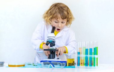 Test tüpleri, reaktörleri ve mikroskobu olan bir çocuğun laboratuvar incelemesi. Seçici odaklanma. çocuk.