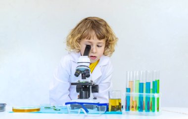 Test tüpleri, reaktörleri ve mikroskobu olan bir çocuğun laboratuvar incelemesi. Seçici odaklanma. çocuk.