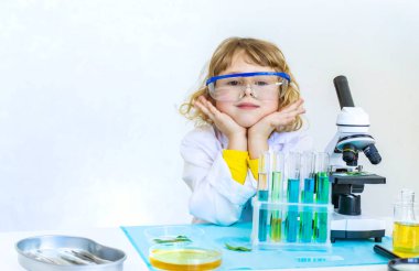 Test tüpleri, reaktörleri ve mikroskobu olan bir çocuğun laboratuvar incelemesi. Seçici odaklanma. çocuk.