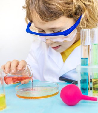 Test tüpleri, reaktörleri ve mikroskobu olan bir çocuğun laboratuvar incelemesi. Seçici odaklanma. çocuk.