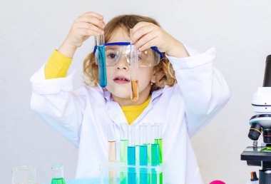 Test tüpleri, reaktörleri ve mikroskobu olan bir çocuğun laboratuvar incelemesi. Seçici odaklanma. çocuk.