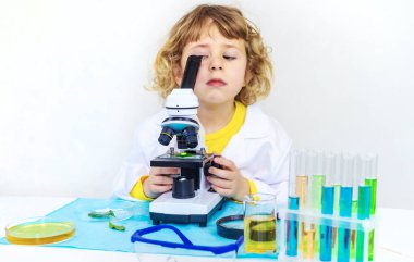 Test tüpleri, reaktörleri ve mikroskobu olan bir çocuğun laboratuvar incelemesi. Seçici odaklanma. çocuk.