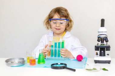 Test tüpleri, reaktörleri ve mikroskobu olan bir çocuğun laboratuvar incelemesi. Seçici odaklanma. çocuk.