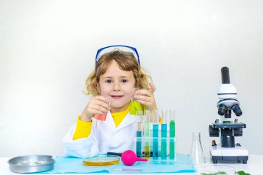 Test tüpleri, reaktörleri ve mikroskobu olan bir çocuğun laboratuvar incelemesi. Seçici odaklanma. çocuk.