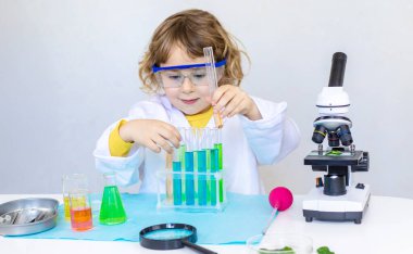 Test tüpleri, reaktörleri ve mikroskobu olan bir çocuğun laboratuvar incelemesi. Seçici odaklanma. çocuk.