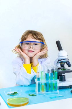 Test tüpleri, reaktörleri ve mikroskobu olan bir çocuğun laboratuvar incelemesi. Seçici odaklanma. çocuk.