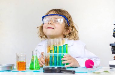 Test tüpleri, reaktörleri ve mikroskobu olan bir çocuğun laboratuvar incelemesi. Seçici odaklanma. çocuk.