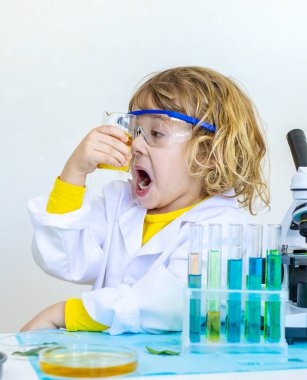 Test tüpleri, reaktörleri ve mikroskobu olan bir çocuğun laboratuvar incelemesi. Seçici odaklanma. çocuk.