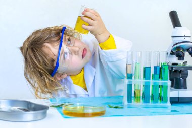 Test tüpleri, reaktörleri ve mikroskobu olan bir çocuğun laboratuvar incelemesi. Seçici odaklanma. çocuk.