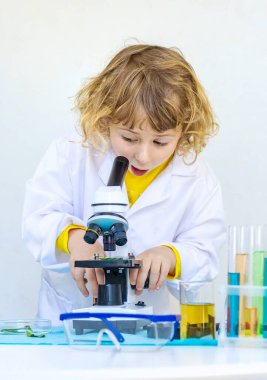 Test tüpleri, reaktörleri ve mikroskobu olan bir çocuğun laboratuvar incelemesi. Seçici odaklanma. çocuk.