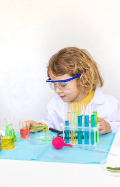 Test tüpleri, reaktörleri ve mikroskobu olan bir çocuğun laboratuvar incelemesi. Seçici odaklanma. çocuk.