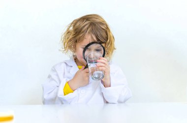 Bir çocuk suyu büyüteçle inceler. Seçici odaklanma. çocuk.